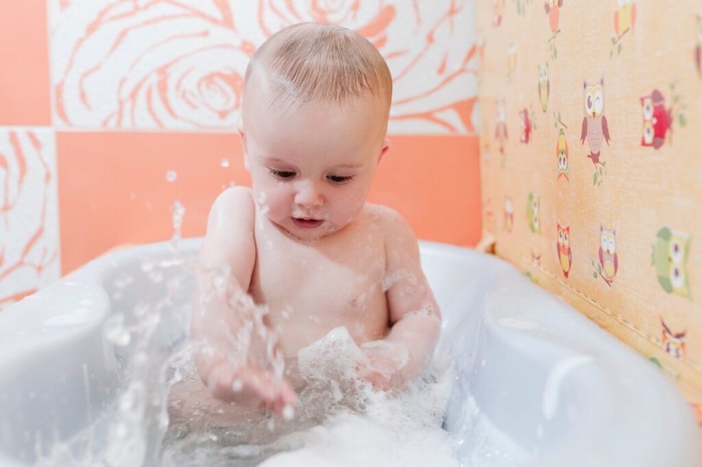sweet baby taking a bath at home and splashing water